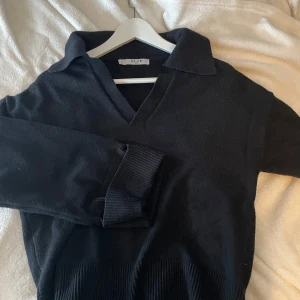 Svart stickad - Snygg svart stickad polotröja från NA-KD med v-ringning och krage. Tröjan har långa ärmar och ribbade muddar vid ärmslut och nederkant. Passar även S