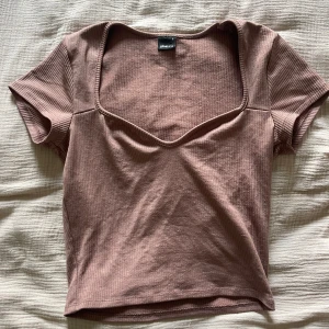 Ribbad brun/rosa topp från Gina Tricot - Säljer en ribbad brun/rosa topp från Gina Tricot i storlek S. Toppen har korta ärmar, croppad passform och en snygg v-ringad halsringning🩷🤎