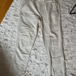 Beiga linnebyxor från Zara med snörning - Säljer ett par beiga linnebyxor från Zara i storlek S. Byxorna har elastisk midja med snörning och raka ben. Perfekta för chill dagar eller när du vill ha en avslappnad stil. 
