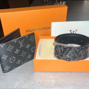 Louis Vuitton plånbok och bälte i monogram - Snygg plånbok från Louis Vuitton i svart skinn med klassiskt monogrammönster i grått. Plånboken har flera fack för kort och sedlar, perfekt för dig som vill ha en stilren och lyxig accessoar. Ikonisk LV-logga och exklusiv känsla. Bältet är perfekt för dig som vill ha ett enkelt och stiligt bälte som funkar till allt.