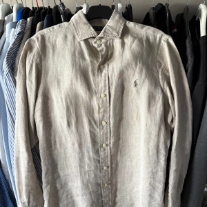 Linneskjorta Ralph Lauren - Snygg beige skjorta i linne från Polo Ralph Lauren. Använd 2-3 gånger MAX så skicket är som nytt. Storlek : SP: Sitter som en M/L