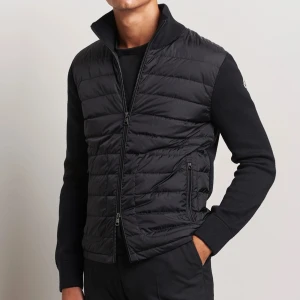 Moncler Hybrid Zip Cardigan Black - Svart quiltad jacka från Moncler med stickade ärmar och vadderad front. Jackan har dragkedja framtill, ståkrage och två fickor med dragkedja. Snygg och stilren design som passar perfekt till höst och vår. Knappt använd. NYPRIS ca 10 000kr. Kvitto finns vid intresse