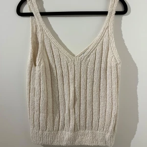 Beige ribbad stickad linnetopp - Säljer en beige stickad linnetopp med ribbad struktur och v-ringning. 