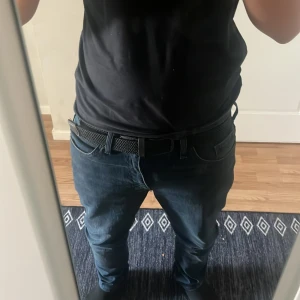 Svart flätat bälte med skinn-detaljer - Säljer ett svart flätat bälte med snygga skinn-detaljer vid spännet. Bältet har ett matt svart metallspänne och är flexibelt tack vare det flätade materialet. Passar perfekt till jeans eller chinos för en stilren look. Jätte lätt och nice och passar med alla outfits 