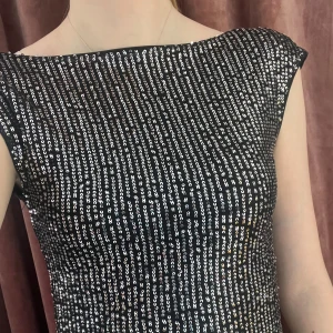 Glittrig croppad topp med öppen rygg - Säljer en svart croppad topp med silvriga paljetter. Toppen har breda axelband och en djup öppen rygg som gör den extra snygg. Perfekt för dig som vill sticka ut och glänsa på festen!
