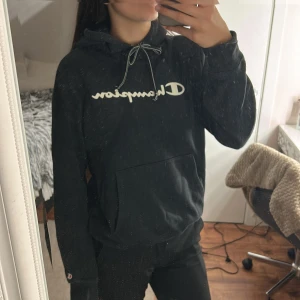 Svart Champion hoodie XL, men är som S/M i storleken  - Svart hoodie från Champion i storlek XL med vit logga framtill och klassisk känguruficka. Tröjan har huva med snörning och ribbade muddar vid ärmslut och nederkant. Perfekt för chill dagar eller när du vill ha en sportig look.