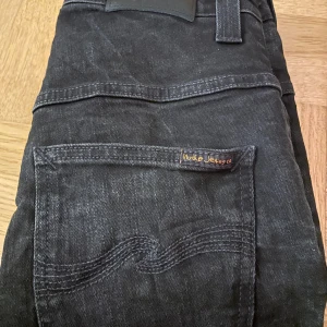 Svarta jeans från Nudie Jeans, W31 L32 - Säljer ett par svarta jeans från Nudie med slim fit utan slitage eller fläckar, som nya.
