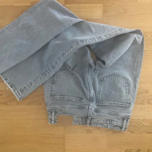 Grå wide jeans från Zara - Säljer ett par gråa jeans från Zara med breda ben och klassiska femficksdetaljer. Jeansen har en ljusgrå tvätt och raka, lite fransiga benslut för en chill vibe. Perfekt för dig som gillar loose fit och vill ha en cool streetstil.