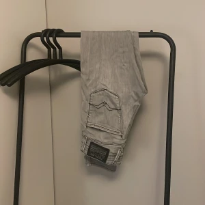Replay Anbass ljusgrå jeans - Säljer ett par snygga Replay Anbass jeans i ljusgrå tvätt med svarta kontrastsömmar. Klassisk femficksmodell med Replay-logga på bakfickan. Jeansen har en slim passform och är tillverkade i mjukt jeanstyg som sitter skönt. Har vanligtvis 29 i W men dessa har suttit bra under hela tiden jag har ägt dem. Skriv om det är något otydligt.
