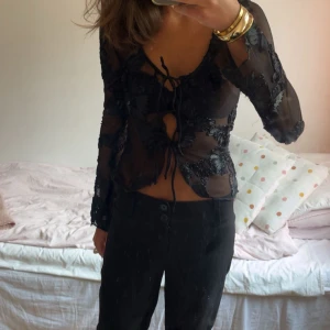Svart fest topp  - Säljer en svart transparent blus med långa ärmar och broderade blommor, perfekt till fest. Toppen är i mycket bra skick, endast använd en gång. Hör av dig vid intresse 
