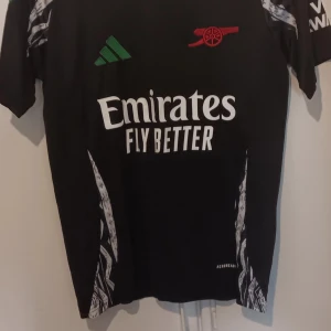 Declan rice arsenal jersey - Svart Arsenal fotbollströja från Adidas med grönt och rött tryck på bröstet, Emirates Fly Better sponsorlogga och vita detaljer på sidorna. Ryggen har Rice och nummer 41 i vitt. Slim fit, kortärmad och tillverkad i lätt funktionsmaterial.