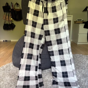 Svartvita rutiga pyjamasbyxor  - Snygga byxor med svartvitt rutigt mönster och breda ben i storlek Xs.De har elastisk midja med snörning för skön passform. Perfekta för en chilll kväll hemma. Dem har inga defekter!!! Kontakta mig om du har några funderingar!!❤️