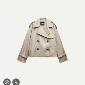 Beige trenchcoat från Zara - Snygg beige trenchcoat från Zara med dubbelknäppning och stora svarta knappar. Jackan har klassisk krage, bälte vid ärmsluten och en loose fit som ger en chill vibe. Perfekt för lager-på-lager och funkar till allt. Materialet är bomull och polyester.