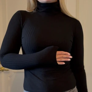 Svart ribbad polotröja - Svart ribbad polotröja ifrån Nelly med lång ärm och tight passform. Storlek XS, fint skick! 