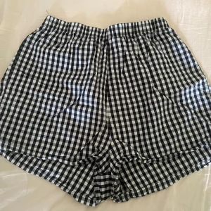 Svarta rutiga shorts - Rutiga shorts från Stradivarius i svart och vitt, med elastisk midja och loose passform. Klassisk rutig design.