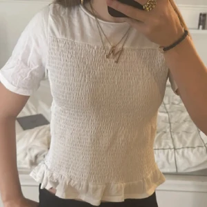 Vit blus med volangkant - Supersöt vit blus med smockad front och volangkant längst ner. Från Gina tricot, storlek 158-164