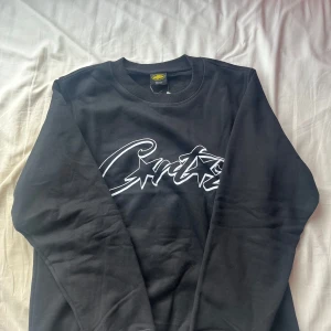 Svart oversized tröja från Corteiz med tryck - Svart crewneck-tröja från Corteiz med stort vitt grafiskt tryck på bröstet. Klassisk rund halsringning och ribbade muddar. Tröjan är i bomull och har en clean streetwear-look. Storlek S men är overzised så den passar M. Aldrig använd.