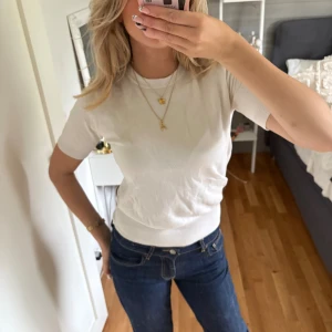 Vit basic t-shirt i bomull - Säljer en enkel och stilren vit t-shirt med rund hals och korta ärmar. T-shirten har en klassisk passform och är gjord i mjuk bomull, perfekt att matcha med jeans eller kjol för en clean look.