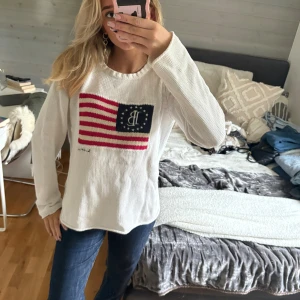 Vit stickad tröja från Lexington - Vit stickad tröja från Lexington med amerikansk flagga och broderad logga på bröstet. Tröjan har rund halsringning och långa ärmar. Perfekt för dig som gillar klassisk och preppy stil. ! Tröjan har en mindre fläck i mitten (syns inte mer än det som framgår i bilden) men detta kan jag sjävklart skicka bild på vid intresse ❤️