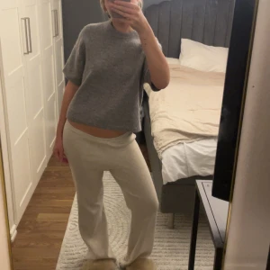 Grå stickad T-shirt Gina tricot - Supermjuk grå stickad tröja från Gina Tricot i ullmix. Modellen är boxig och croppad med korta ärmar och rund halsringning. Perfekt att slänga på sig över ett linne eller t-shirt för en chill look.