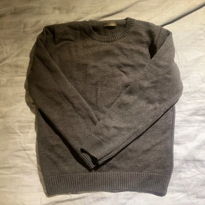 Mörkgrå merinoullströja Stenströms - Säljer en stilren mörkgrå stickad tröja från Stenströms i 100% merinoull. Tröjan har rund halsringning, ribbade muddar och är långärmad. Perfekt för lager-på-lager och passar till både jeans och kostymbyxor.