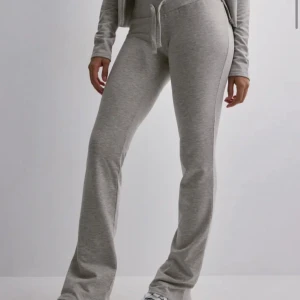 Grå mjukisbyxor med snörning - Snygga grå mjukisbyxor med bootcut-snitt och snörning i midjan. Byxorna är tillverkade i mjukt bomullsmaterial och har en relaxed passform som är perfekt för chill dagar. Enkla att matcha med hoodies eller crop tops.