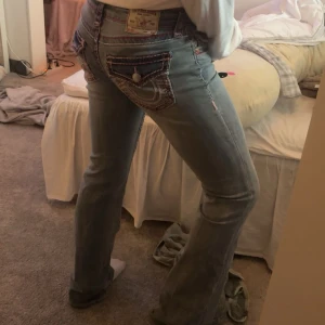 True Religion ljusblå bootcut jeans - Säljer ett par ljusblå jeans från True Religion med snygga kontrastsömmar och detaljerade bakfickor med lock och knapp. Jeansen har bootcut-modell. Bara andvänt 4 gånger utmärkt skick original pris 2200