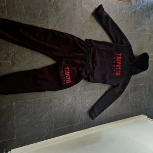 Svart Trapstar London Set - Svart Set från Trapstar London med röd logga. Tröjan har huva, magficka och långa ärmar. Snygg streetwear-vibe och passar dig som gillar bold prints. Byxorna tillkommer. Materialet är mjuk polyester med rätt så dålig kvalitet.