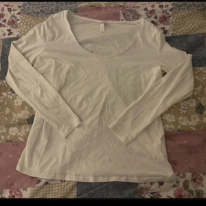 Vit långärmad topp från H&M - En enkel och stilren vit långärmad topp från H&M Basics i storlek XL. Toppen har rundad halsringning och är gjord i mjuk bomull, perfekt för en chill och clean look. Passar dig som gillar basic och bekvämt.
