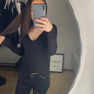 Svart långärmad v-ringad tröja - Säljer en svart långärmad tröja med snygg v-ringning. Modellen är slim och sitter tajt mot kroppen, perfekt för dig som gillar en enkel och stilren look. Passar dig som vill ha en basic topp att matcha med jeans eller kjol.