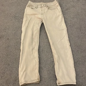 Beiga/gråa slim fit byxor från H&M, stl 140 - Snygga beiga byxor från H&M i slim fit-modell med justerbar midja. Klassisk femficksdesign och raka ben. Perfekta för dig som gillar en stilren och enkel look. Materialet är mjukt och bekvämt, passar till många olika outfits.