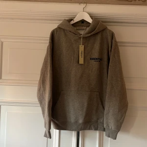 Grå Essentials Fear of God hoodie - Säljer en grå hoodie från Essentials Fear of God i storlek M. Tröjan är såklart autentisk och jätte snygg. Vid minsta fundering om pris eller annat så är det bara att skriva.