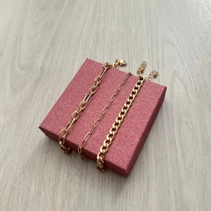 Set med tre guldiga armband - Tre snygga armband i guldfärg med olika kedjedesign. Alla armbanden har enkla lås och är helt nya! Topp skick! De är större i storlek men går att förkorta 