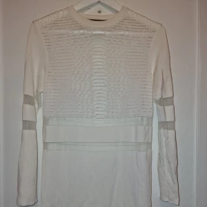 Vit klänning Alexander Wang x H&M - Supersnygg vit stickad tröja från Alexander Wang x H&M med coola transparenta mesh-detaljer på ärmar och över bröstet. Stilren men edgy look. Storlek S men liten I storleken så passar även XS. Liten prick som inte synes väl på bild 3.  