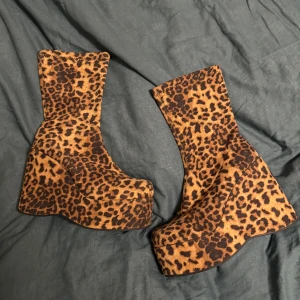 Leopardmönstrade plattformsstövletter - Unika stövletter med högt skaft och fet plattformssula, täckta i leopardmönstrad textil. Perfekt för dig som vill sticka ut och addera lite edge till din outfit. Färgen är brun med svarta leopardfläckar och skon har rund tå. Står storlek 41 men sitter mer som 40!