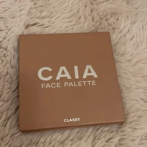CAIA Face Palette Classy - Snygg ansiktspalett från CAIA i färgen Classy. Paletten har en stilren brun förpackning med silvrig text och innehåller flera produkter för ansiktet, perfekt för att skapa en fräsch look.