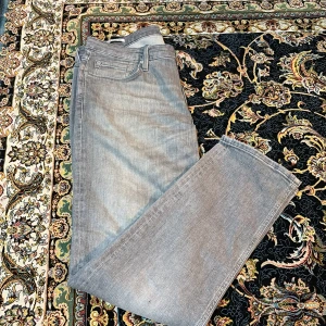 Grå straight jeans från Jack and Jones. Storlek 34/32 - Snygga grå jeans från Levi's med klassisk femficksdesign och raka ben. Jeansen har en neutral grå tvätt och är tillverkade i mjukt jeanstyg med knapp och dragkedja framtill. Perfekt för dig som gillar en clean och enkel look.