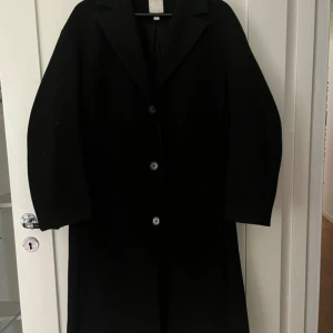 Svart kappa från H&M, storlek S - Snygg svart kappa från H&M i storlek S. Lite nopprig & små hårstrån som sitter på vissa ställen, går säkert att få bort med en roller! Perfekt till höst & vinter