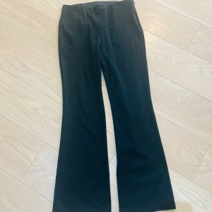 Svarta bootcut byxor från H&M - Svarta bootcut byxor från H&M i storlek 42/ 44. Byxorna har dragkedjor vid bensluten för en extra snygg detalj. De är tillverkade i ett mjukt och stretchigt material som sitter skönt och ger en clean look.