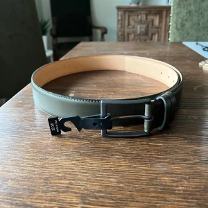 Olivgrönt läder bälte  - Snyggt olivgrönt bälte från Dressmann i äkta skinn, tillverkat i Italien och har ett svart spänne. Bältet är helt nytt och de e bara o höra av sig vid frågor!!🙌