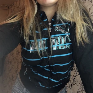Hoodie Puma - En Pumahoodie med dragkedja i färgerna blå och svart. Hoodien är använd men är i ett bra skick. Texten ”Puma” och loggan är täckta med rhinestones, dock är några stenar borta. På lappen står det strl XL men är som en S/M då den är liten i storleken. Meddela mig vid fler frågor!😊