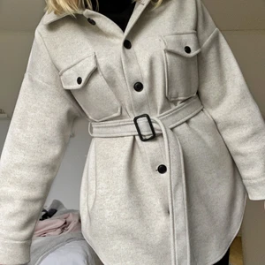 Beige kort kappa - Beige kort kappa med knäppning i midjan från Nelly i storlek 36 (S). Köpt för 2 år sedan & använd några gånger med är i väldigt fint skick. Säljer pga att den inte längre används.