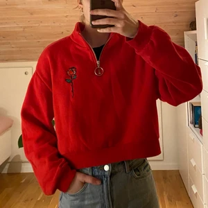 Croppad sweatshirt röd - Röd croppad sweatshirt med dragkedja och broderad ros på bröstet. Mjuk och skön insida. H&M strl. M, jag är 165 cm lång. 
