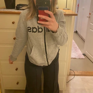 Adidas hoodie grå - Denna tröja är lite kortare och mindre men funkar för både tjejer och killar. Ärmarna är ganska korta så skulle nog säga XS och det är ett adidastryck på framsidan och på luvan. Luvan är inte jättestor men cute. Jättegosigt material och sitter fint.