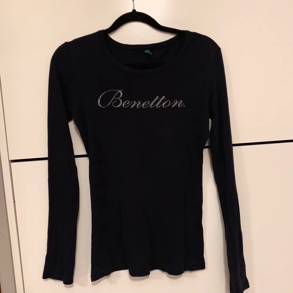 En tröja ifrån Benetton som är figursydd, stretchig och märkets namn på bröstet är i glitter. HALVA PRISET PÅ FRAKTEN . Toppar.