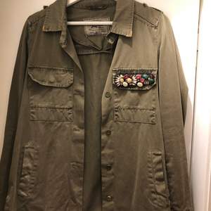 Militärgrön jacka med detaljer på fickan och kragen. Använd enstaka gång, som ny.