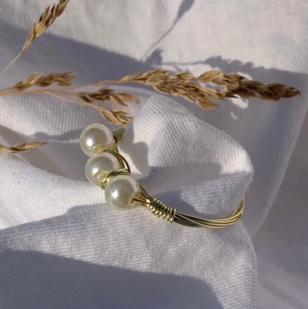Handgjord ring med offwhite pärlor, och guldpläterad koppartråd.  Storlek: 17mm, 18mm (Innerdiametern på ringen). Accessoarer.