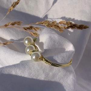 Handgjord ring med offwhite pärlor, och guldpläterad koppartråd.  Storlek: 17mm, 18mm (Innerdiametern på ringen)