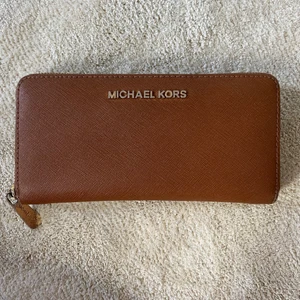 Michael Kors Plånbok - Brun plånbok från Michael Kors med fuldfärgad dragkedja. Fint skick, endast lite sliten i guldfärgen. 