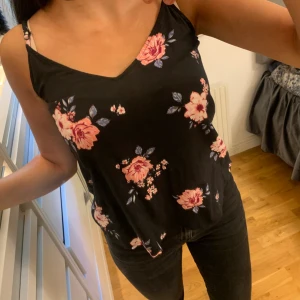 Blommigt linne - Svart linne med rosa blommor, den är i storleken Xs.